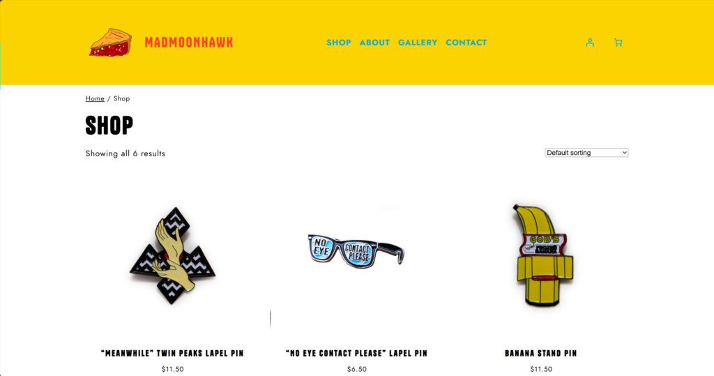 snapshot of a webpage that's titled "shop" with a few different items; lapel pins, and t shirts