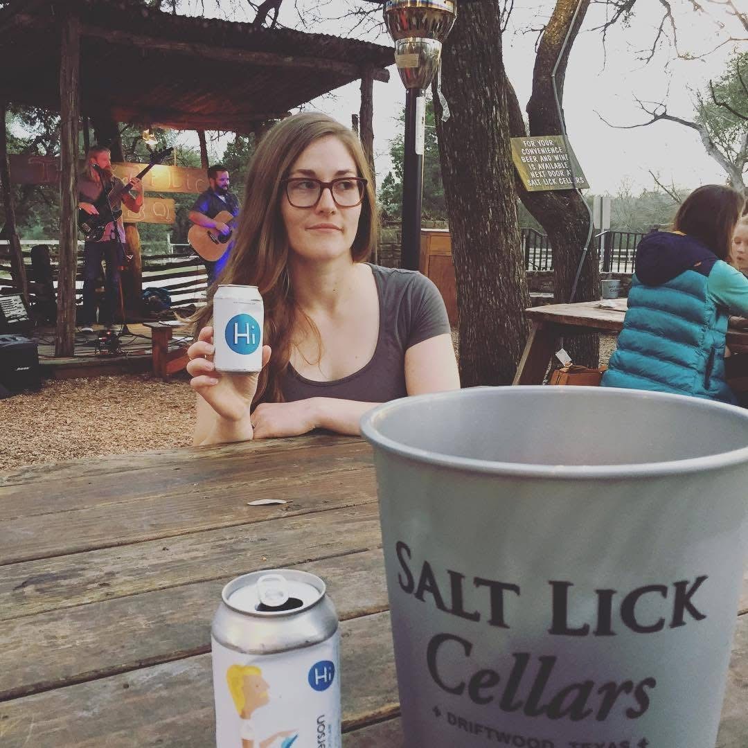 woman holding a can that says "hi", with a bucket in the foreground that says "salt lick cellars"